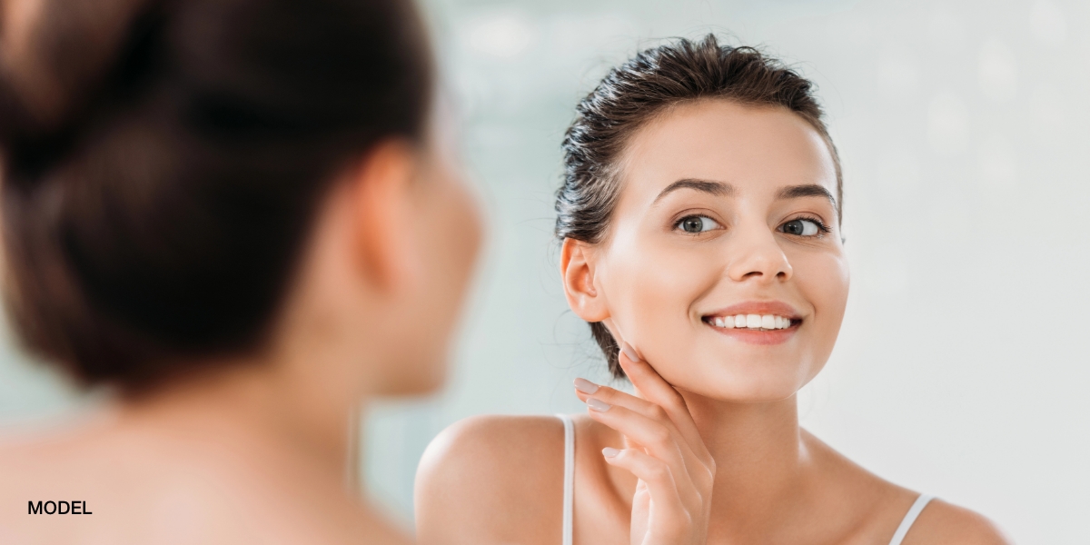 medspa patient glowing skin looking in mirror san antonio | The Heights Plastic Surgery Medspa medspa patient glowing skin looking in mirror san antonio
